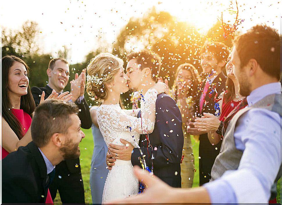 Groom and bride at a wedding kissing surrounded by guests